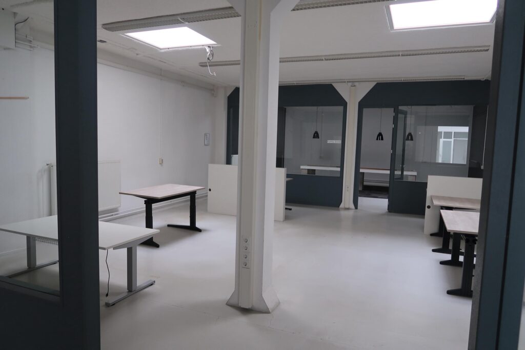 Lichte, lege kantoorruimte aan het Gedempt Hamerkanaal met meerdere bureaus en glazen vergaderruimtes.